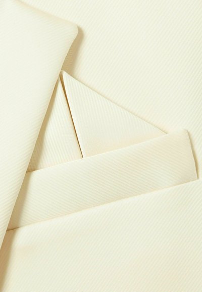 Tissu beige texturé avec des rayures diagonales, présentant un mouchoir de poche plié et un revers. Des bords propres et lisses rehaussent l'apparence sur mesure.