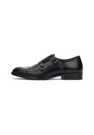 Chaussure habillée en cuir noir avec un bout arrondi, des accents à double boucle et un petit talon. Texture lisse et design minimaliste.