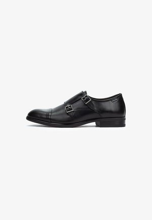 Zapato de vestir de cuero negro con puntera redondeada, acentos de doble hebilla y tacón bajo. Textura suave y diseño minimalista.