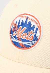 Krémová baseballová čepice s modro-oranžovou vyšívanou kulatou nášivkou s nápisem "Mets", městským panoramatem, mostem a detaily baseballových švů.