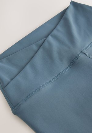 Sinine sportkangas, millel on sile tekstuur ja mis on ülevalt korralikult kokku volditud. Servas jookseb lame õmblus, mis rõhutab lihtsat kujundust.