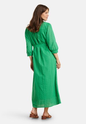 Groene maxi-jurk met een textuurpatroon, een smalle taille en driekwartmouwen. De stof is lichtgewicht met een subtiel gaatjesontwerp.