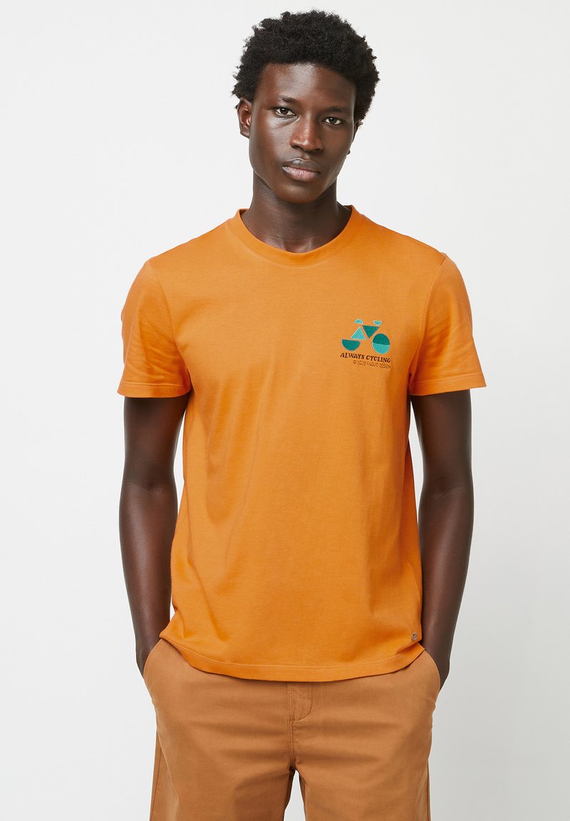 Korte mouwen oranje katoenen T-shirt met een geborduurd ontwerp van een blauwe en groene fiets en de tekst "ALTIJD FIETSEN" op de borst.