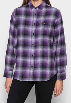 Lila-schwarzes kariertes Flanellhemd mit langen Ärmeln, Knopfleiste vorne und kleinem goldfarbenem Logo auf der Brust. Strukturierter Stoff.