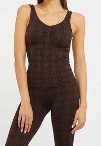 Brun ribbet tanktop med et struktureret mønster i mørkebrun. Har en scoop halsudskæring og tynde stropper. Tæt siddende design.