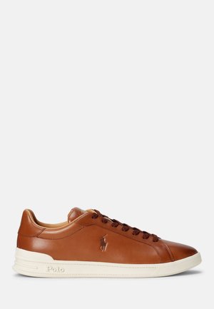 Baskets basses en cuir marron avec lacets marron foncé, logo Polo embossé sur le côté et semelle en caoutchouc blanche sur fond uni.