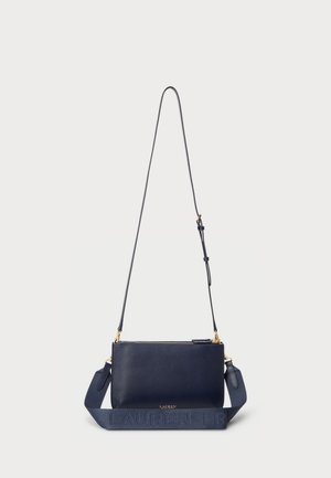 Donkerblauwe rechthoekige leren crossbodytas met goudkleurige rits en beslag, voorzien van een verstelbare dunne band en een brede stoffen schouderband met merknaam.