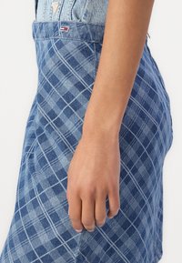 Jeanskjol i blå nyanser med rutig mönster. Har en strukturerad form och kontrasterande sömmar. Logotypdetalj på midjebandet.