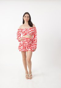 Rood-witte zebra-gepatroonde twee-delige set met een off-the-shoulder top met lange mouwen en een flared minirok.