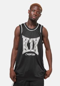 Maillot de basket sans manches noir avec le texte blanc « K1X » et « On My Way » dans un design en motif serpent, avec une bordure blanche le long de l'encolure.