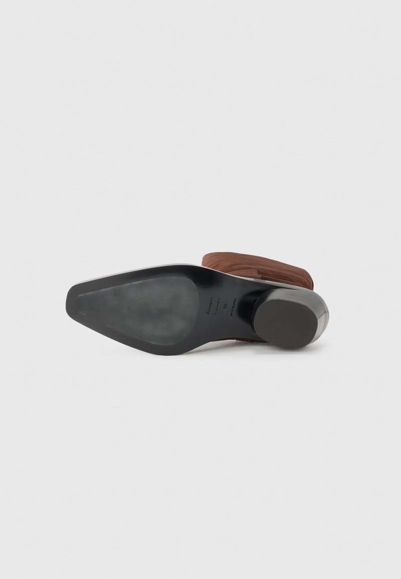 Brown heeled shoe with a smooth, rounded design. Features a black rubber sole and a sturdy heel. Texture appears soft and flexible.