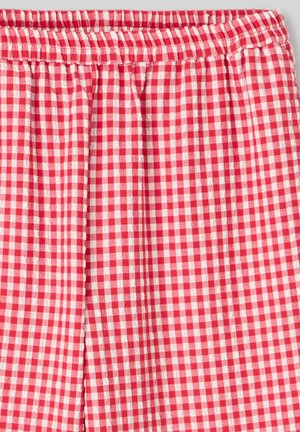 Tissu à carreaux rouge et blanc avec une taille élastique, présentant une texture légère et des détails froncés le long du bord supérieur.
