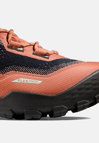 Oranje en zwarte trailschoen met een gestructureerde mesh bovenkant, versterkte neus en stevige zwarte zool. Bevat "FLEXTRON" branding.