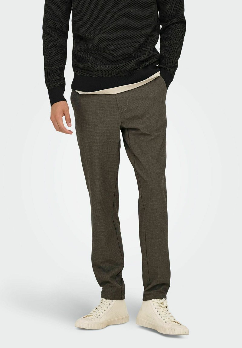 Men's dark green textured trousers with a straight-leg fit, paired with a light beige t-shirt and white sneakers. No visible patterns or hardware.