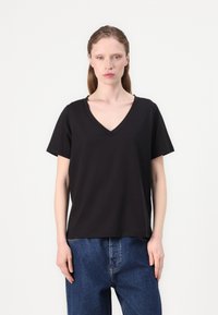 Black V-neck t-shirt made of soft fabric, featuring short sleeves and a relaxed fit. Worn with blue denim pants.