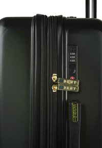 Maleta rígida negra con líneas horizontales, dos cremalleras doradas, un candado de combinación y un asa retráctil para mayor comodidad.