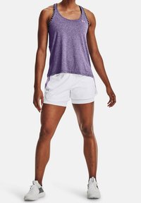 Lila sportlinne med svarta och vita axelbandsdetaljer, kombinerat med vita shorts med lila sidopanel, bärs med vita sportskor.