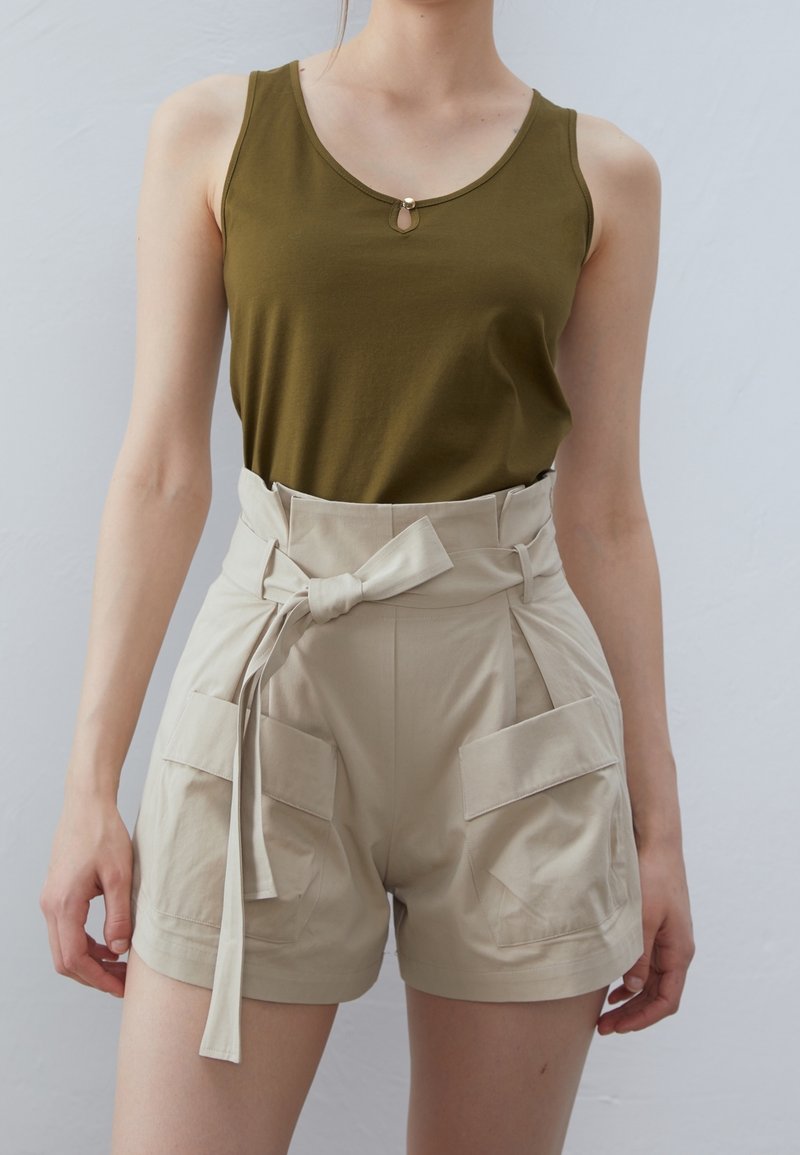 Olijfgroen mouwloze top met een ronde accent, gecombineerd met hoge beige shorts met een gestrikt ceintuur en twee voorkruiszakken.