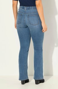 Jeans a zampa d'elefante in denim blu con un alto girovita elasticizzato, due tasche posteriori e una leggera scoloritura. Le gambe si restringono leggermente verso l'orlo.