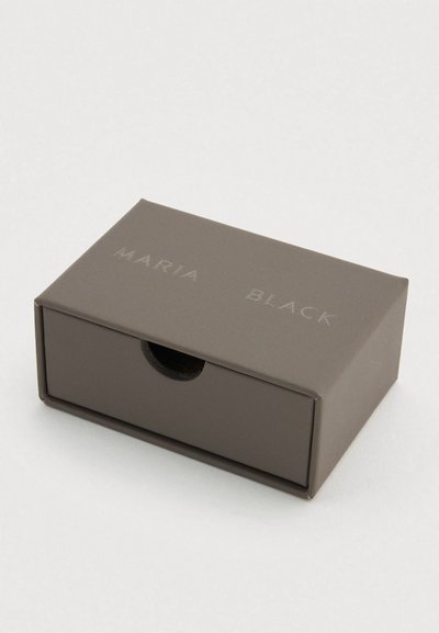 Dunkelgraue rechteckige Box mit einem erhabenen Logo mit der Aufschrift "MARIA BLACK." Verfügt über ein herausziehbares Design und eine glatte, matte Oberfläche.
