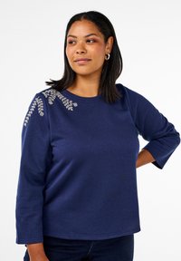 Marinblå långärmad t-shirt i mjukt tyg med blommig broderi på axeln, med rund halsringning och avslappnad passform.