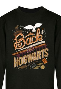 Black sweatshirt featuring a graphic design with the text "Back to Hogwarts," owls, broomsticks, and Hogwarts Train.