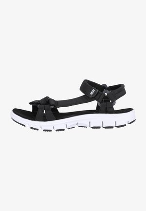 Musta sandaali, jossa on kangas päällinen ja säädettävät hihnat, sekä valkoinen ja musta pehmustettu pohja, jossa on teksturoitu kulutuspinta.