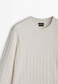 Pull en maille torsadée couleur crème avec manches longues et col rond côtelé, présenté à plat.