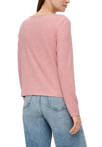 Helles rosa Langarmoberteil aus weichem, strukturiertem Stoff. Hat eine lockere Silhouette mit einem Bootsausschnitt, kombiniert mit hochtaillierten Denim-Jeans.