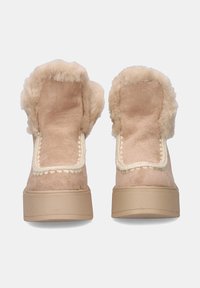 Botas beige con cuello de piel sintética suave, parte superior de ante, detalles cosidos y una suela de plataforma sólida de color crema.