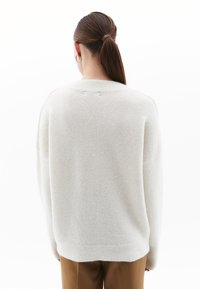 Maglione oversized color beige chiaro realizzato in tessuto morbido e testurizzato. Caratterizzato da un collo rotondo e spalle scese, con polsi e orlo a coste.