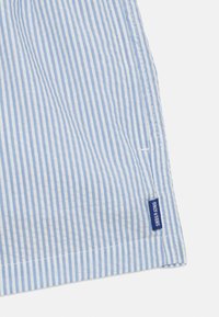 Tissu striped bleu et blanc avec de fines rayures verticales. Présente un ourlet avec une étiquette bleue portant la mention "Only & Sons" sur le bord inférieur.