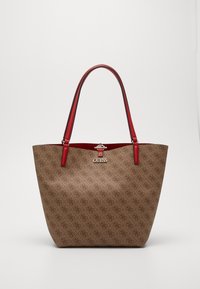 Hnědá vzorovaná taška přes rameno s červenými koženými uchy a stříbrným kováním. Obsahuje logo na přední straně a má strukturovaný tvar.
