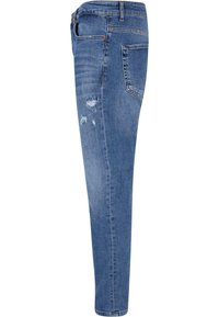 Jean en denim bleu à coupe ajustée, présentant des détails usés sur la cuisse et la poche arrière, design classique à cinq poches, et coutures surpiquées.