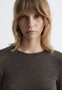 Dark brown, ribbed knit top with a rounded neckline. Soft texture, fitted design, and short sleeves. Simple style without additional patterns or accents.