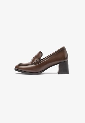 Mocassins à talons en cuir marron avec un bout rond, un accent cousu sur le empeigne et un talon bloc texturé.