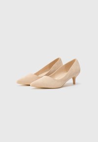 Zapatos de tacón alto de ante beige con punta afilada y un tacón tipo kitten bajo. Textura suave con un diseño simple y clásico.