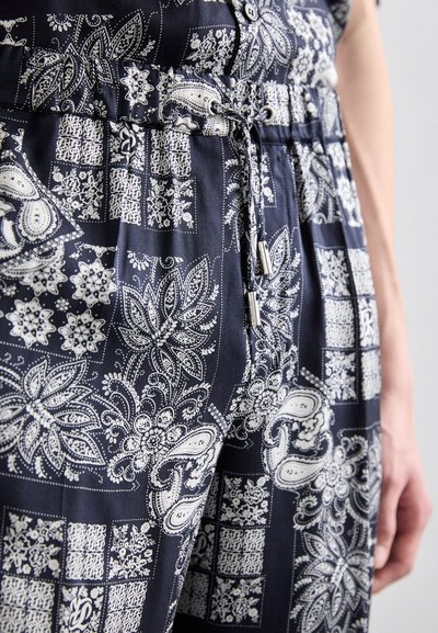Navy patterned fabric with white paisley and floral designs. Drawstring waist with metallic aglets and button details. Soft texture.