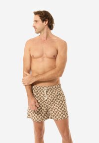 Costumi da bagno marroni con motivo, dotati di cintura con coulisse, caratterizzati da un design geometrico con accenti beige e rossi. Tessuto leggero, lunghezza fino a metà coscia.