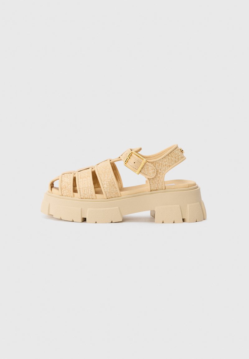 Beige platform sandals with woven straps and a buckle. Chunky sole with textured finish. Open toe design. Lightweight and casual.