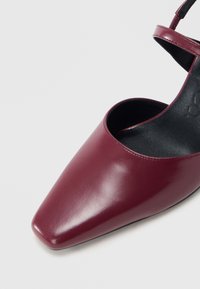 Bourgondische leren schoen met een spitse neus, open zijkanten en een slanke enkelband. Gladde textuur met een glanzende afwerking.