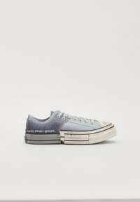 Niedrigschnitt-Sneaker mit einem Obermaterial aus einem blauen bis grauen Farbverlauf aus Canvas, beigem Gummispitzenkappe und einer weißen Sohle mit schwarzen Akzenten. "Feng Chen Wang" Branding ist enthalten.