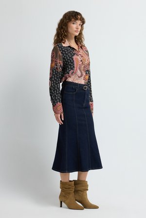 Chemisier à manches longues avec motif paisley ; jupe A-line en jean foncé avec des détails de couture ; bottines en daim marron avec des pointes.