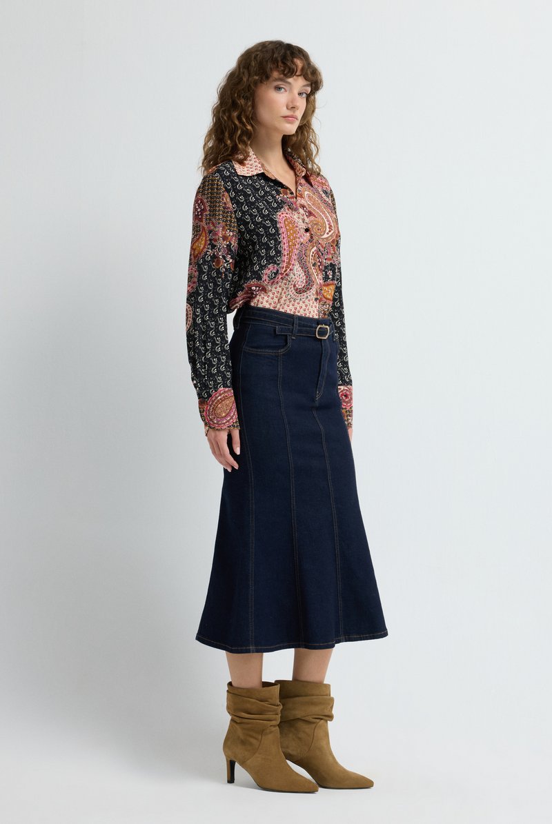 Blusa de manga larga con estampado de paisley; falda A-line de mezclilla oscura con detalles de costura; botines de ante marrón con puntera afilada.