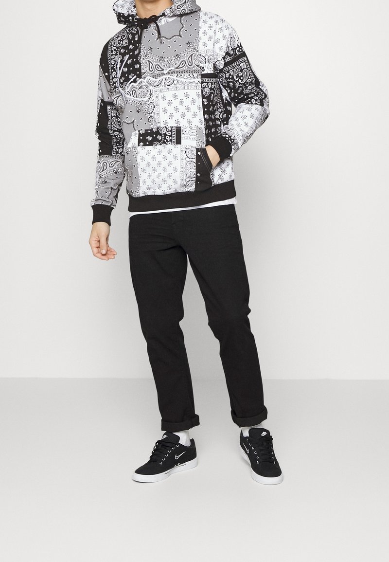 Hoodie i svart och vitt bandanamönster med dragsko i huvan, ficka fram och svarta ribbade muddar. Matcher med svarta byxor och sneakers.