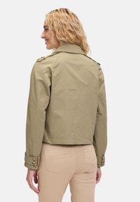 Khaki cropped jack met een kraag, schouderepauletten en knoopmanchetten. Glad stof met minimale textuur.