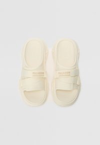Lyse beige sandaler laget av slitesterkt materiale med strukturert såle, to justerbare stropper og tråkket såle for bedre grep.