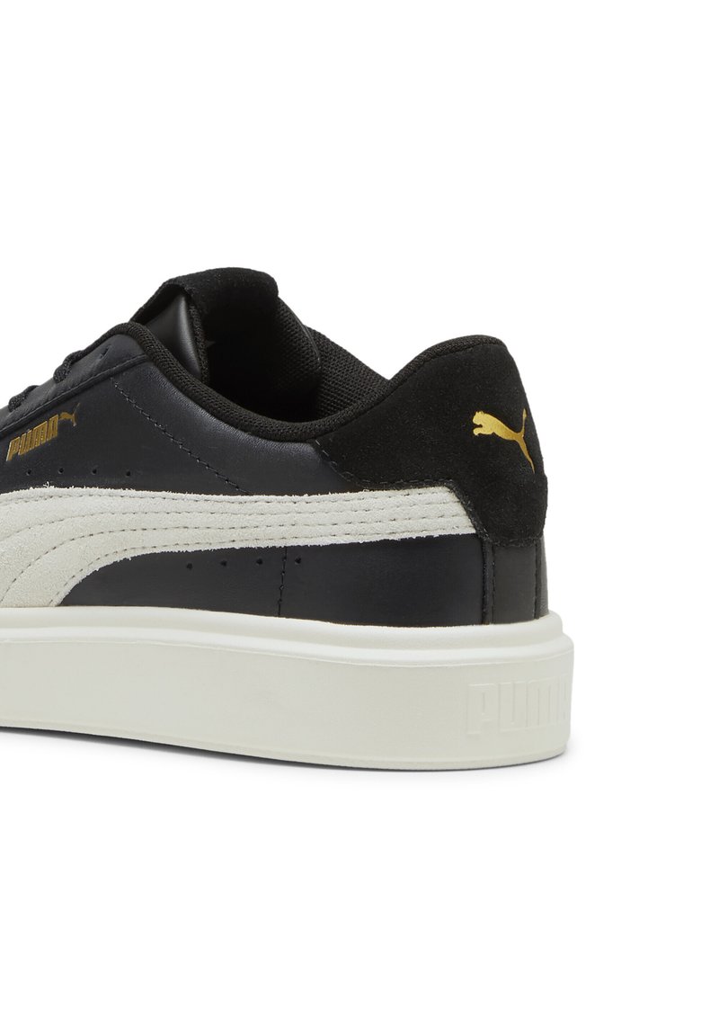 Baskets en cuir noir avec des accents en suede noir texturé, une rayure blanche texturée, et des détails en or du logo Puma sur le talon et le côté.