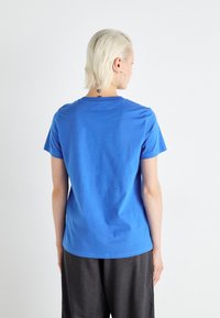Camiseta de algodón azul con mangas cortas y escote redondo. La parte trasera es lisa, sin gráficos ni adornos.
