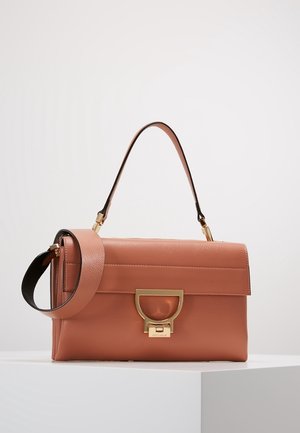 Bolso de mano de cuero marrón con asa superior y correa de hombro desmontable, con un cierre de tono dorado sobre una superficie blanca.